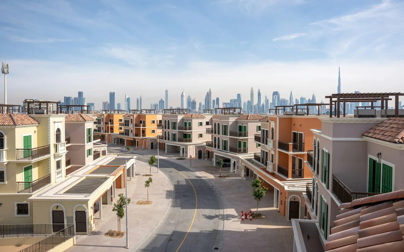 Townhouses on a community street with the Dubai skyline behind