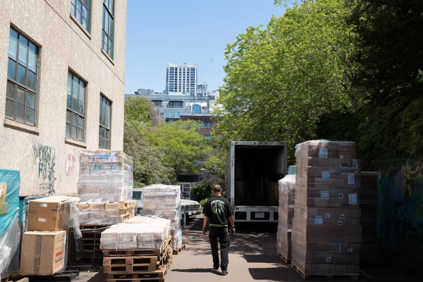 Pallets of boxed stock and packaging stacked beside a lane where a truck waits to be loaded, a typical warehouse clearance setup in Dubai